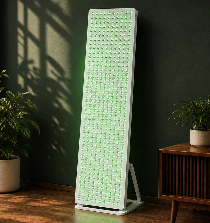 Calmlyte Studio Panel standing on its floor stand against a deep green wall between two potted plants, its full-height green LED array lit